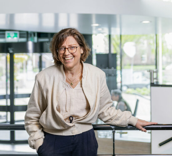 Christa staat in het gemeentehuis. Achter haar zie je de ingang.