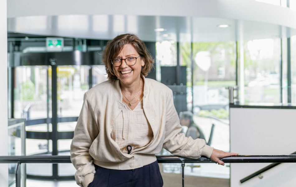 Christa staat in het gemeentehuis. Achter haar zie je de ingang.